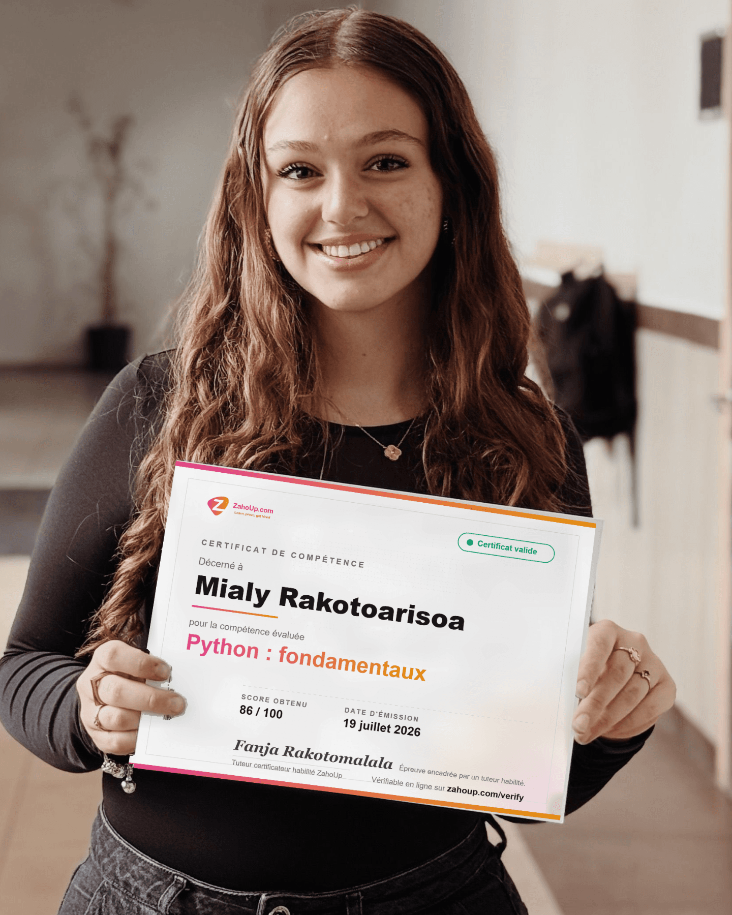 Une apprenante tient son certificat de compétence ZahoUp : score obtenu, tuteur certificateur et adresse de vérification en ligne.